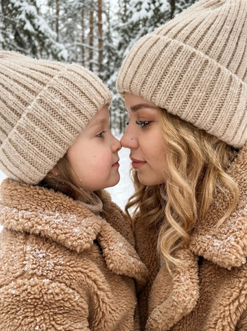   
Создай портрет, не меняя черты лица.
Крупный план, профиль матери и ребенка,
они нежно соприкасаются носами в
заснеженном лесу. На них надеты уютные
вязаные шапки бежевого цвета и пушистые шерстяные пальто (тедди-шубки), покрытые

хлопьями свежего снега. Макияж безупречный, волнистые волосы у женщины .
Цветовая палитра в теплых монохромных бежевых и коричневых тонах. Мягкое,
приглушенное освещение зимнего дня, боке на фоне, кинематографичная эстетика,
высокая детализация текстуры шерсти и
снежинок.
