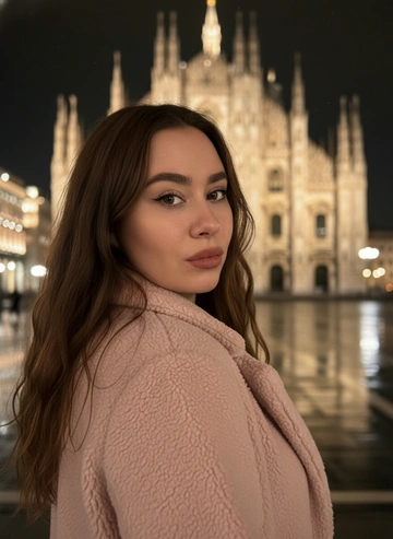 Не менять черты лица и цвет глаз
Девушка 27 лет, среднего телосложения (162 см рост, 74 кг)
Создать крупный портрет женщины, стоящей спиной ночью на фоне освещенного тёплым светом Миланского собора. Со спины видно нежно розовое пушистое пальто.Девушка поворачивается к камере через левое плечо, в то время как мягкая вспышка камеры запечатлевает ее на месте. Волосы распущены и красиво растрепанны от ветра. Кинематографическое, настроение освещения с теплым золотистым боке с отражениями от мокрого асфальта. Подчеркни глянцевую текстуру кожи, насыщенный черный цвет и теплые шо тона, а также небольшую глубину резкости и мягкую зернистость пленки. Extreme close-up shot of a faces, macro portrait, only faces visible. Композиция с объектом немного смещенным влево, а роскошный Duomo di Milano виден в блюре справа. Управление камерой: 35 мм.