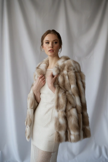 Женщина в студии на белом фоне в роскошной соболиной шубе классического фасона, под шубой изящное белое кружевное платье-футляр. Стоит прямо, слегка наклонив голову, смотрит в камеру, на лице естественный макияж, распущенные волосы аккуратно уложены, образ мягкий и утончённый.