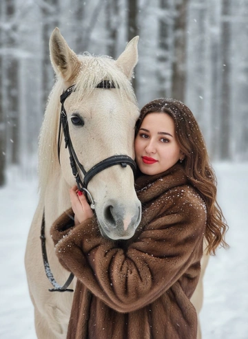  Не меняй внешность девушки, цвет волос На изображении крупным планом показаны девушка и лошадь в зимней обстановке. Снег падает, создавая эффект заснеженности.девушка, одетая в шубу, обнимает лошадь. уДевушка смотрит в камеру и обнимает лошадь.  Волосы распущенны прическа волнистые распущенные волосы На ее губах нанесена красная помада.Лошадь светлой  масти, На голове лошади надета упряжь. Мех и шерсть обоих покрыты снежинками.Фон представляет собой размытый зимний пейзаж с деревьями. На девушке коричневая пушистая шуба 