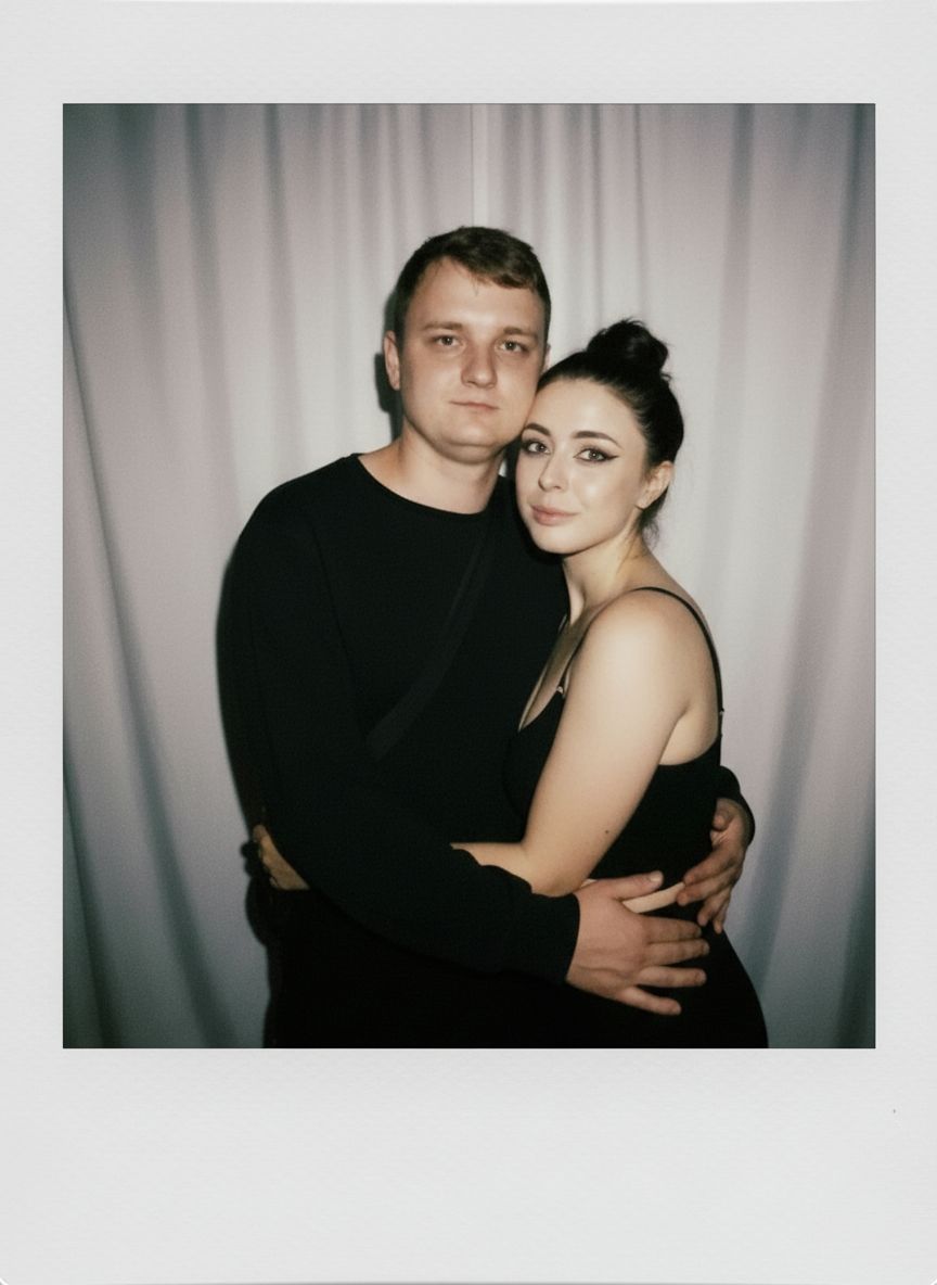 Take a picture with a Polaroid camera. the photo should look like a normal photo, without any clear subject or props. The photo should have a consistent light source such as a flash from a dark room, spread throughout the photo. Do not change the faces. Replace the background behind the two people with a white curtain. Люди на фото обнимаются.