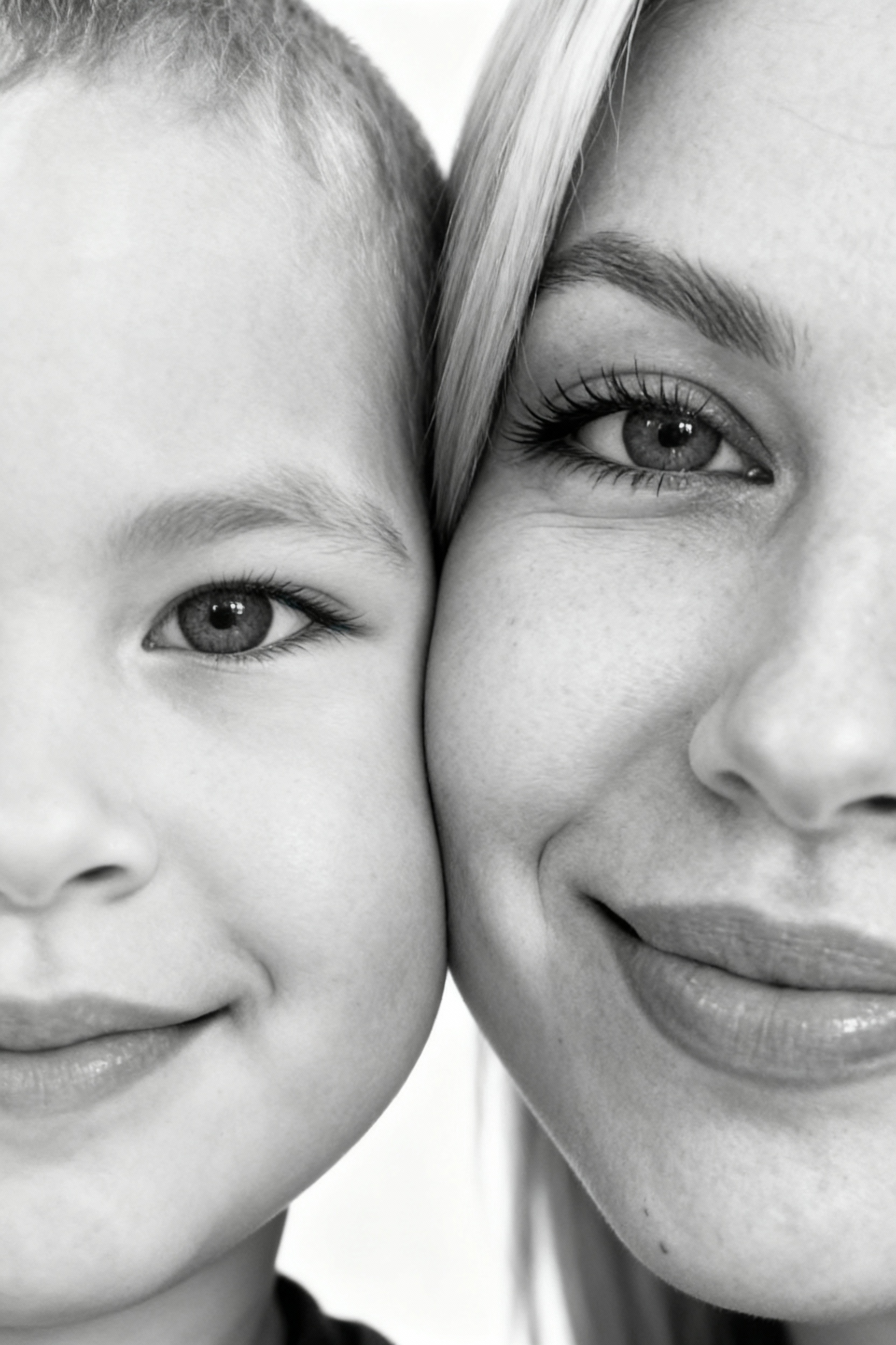 Сверхреалистичная черно-белая художественная фотография 8K женщины и ребенка, снятая очень крупным планом, щека к щеке так что видны только правая половина лица женщины и левая половина лица ребенка. которые смотрят в камеру. Их лица расположены рядом, почти соприкасаясь, образуя идеально сбалансированную симметричную композицию. Каждая деталь передана с фотографической точностью: тонкая текстура кожи и плавные градиенты света и тени. Видимая половина женщины включает ее бровь, один глаз , часть ее носа, щеку и губы, слегка приоткрытые в нежной, естественной улыбке, Видимая половина ребенка включает один глаз , круглую мягкую щеку, часть носа и небольшую улыбку, Фон белый и слегка размытый, что подчеркивает эмоциональную близость между ними. Освещение мягкое и рассеянное, создает деликатный контраст и тональную глубину. На снимке запечатлены нежность, близость и связь между матерью и ребенком, запечатленные с потрясающей реалистичностью. Не меняй черты лиц. 