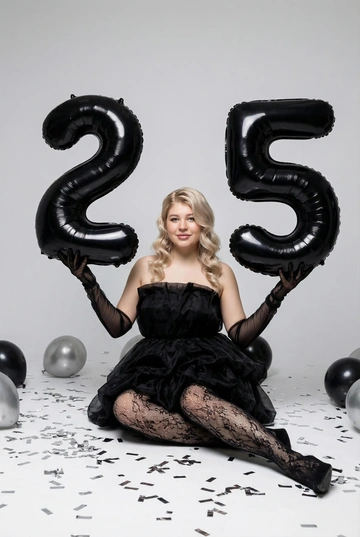 Профессиональная студийная фотосессия ко дню рождения. Не меняй векшность, комплекцию, цвет волос и возраст женщины на первом фото. Светлая фотостудия со светло-серым бесшовным фоном. Женщина одета в чёрное облегающее вечернее платье мини без бретелей и пышной юбкой со сборкой. На ногах — чёрные полупрозрачные колготки с мелким ажурным узором. На руках длинные шифоновые перчатки до локтя.. Образ стильный, женственный, слегка гламурный. Мягкий рассеянный студийный свет, чистые тени, высокая детализация. Атмосфера праздничная, эстетика fashion-редакционной съемки. Реалистичное лицо, естественные пропорции, без искажений. У женщины профессиональная укладка - мягкие глянцевые волны.. Средний план. Человек сидит на полу, в руках большине воздушные черные шары в форме цифр 25, локти слегка согнуты. Взгляд в камеру, акцент на силуэт и шары. Легкая улыбка. На полу вокруг лежат серебристые конфетти, черные и серебристые шары.